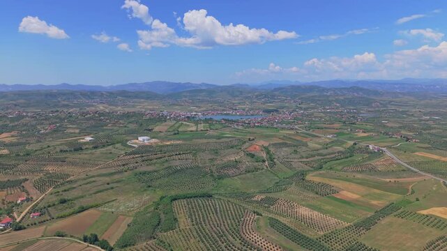 Aerial view of Liqeni i Seferanit surrounded by agricultural fields, olive groves, and the town of Belsh in Belsh, Elbasan County, Albania.