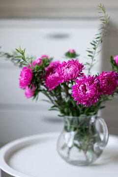 Pink flower bouquet in glass pitcher on white table