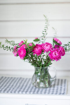 Pink flower bouquet in glass pitcher on kitchen table
