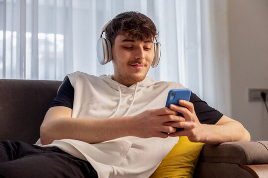 Man with headphones use smartphone on sofa at home