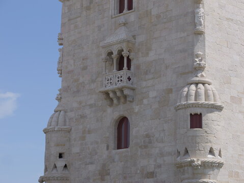 View of the ornate stone facade and architectural details of the historic Belem Tower under a clear blue sky in Lisboa, Lisboa, Portugal.