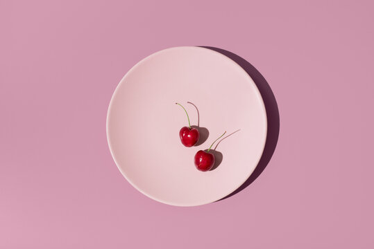 Picota cherries on pink plate with dramatic shadow