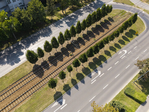 Aerial view of a tram line flanked by rows of trees and a road in Krakow, Lesser Poland Voivode, Poland.