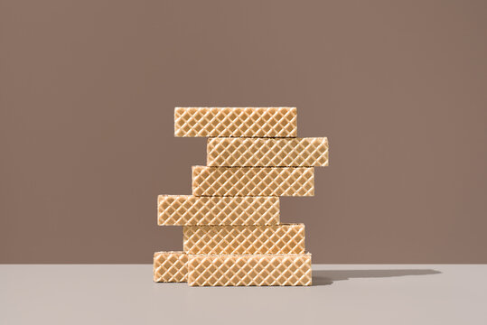 Stack of crispy wafer cookies on brown background