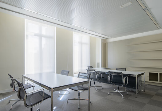 Bright neoclassical office interior with meeting tables and chairs
