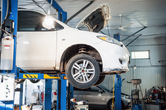 Car suspension inspection on hydraulic lift, automotive diagnostics, maintenance, repair and garage service.