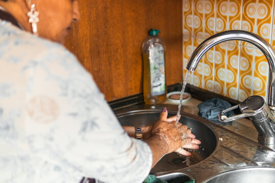 Senior woman wash hands at home kitchen sink