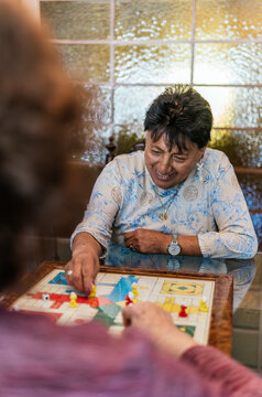 Senior woman enjoy board game with friend at home