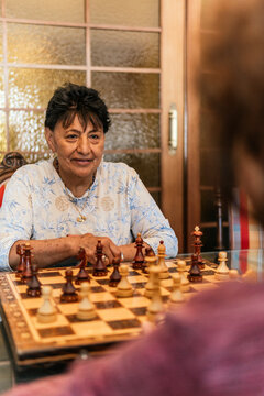 Senior woman play chess at home with opponent