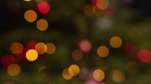 Flashing golden and red bokeh lights creating a magical holiday atmosphere, out of focus christmas tree shining with festive garland, abstract background celebrating winter festivities