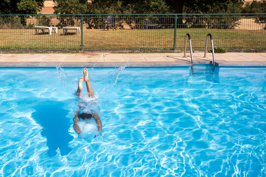 Swimmer dive underwater in outdoor pool with ladder