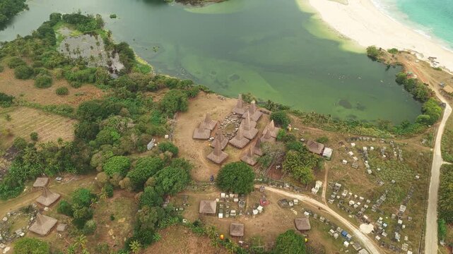 Aerial view of the traditional Ratenggaro village with distinctive high-roofed houses situated near the river mouth and beach in Kodi Bangedo, East Nusa Tenggara, Indonesia.
