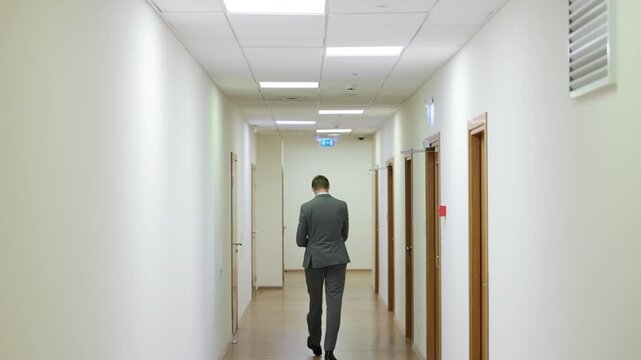 Successful male executive in a formal suit walking through a bright corporate hallway directly towards the camera.Split screen or sequence of a professional businessman walking back and forth in a con