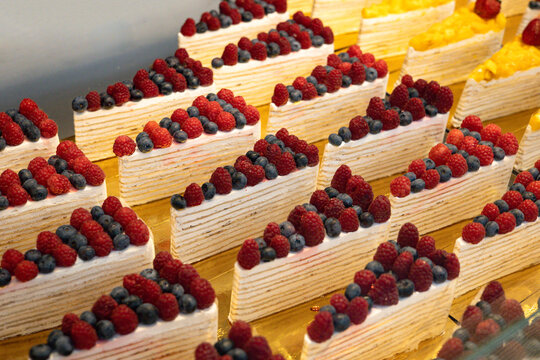 Berry-topped layered cake display at a modern food hall