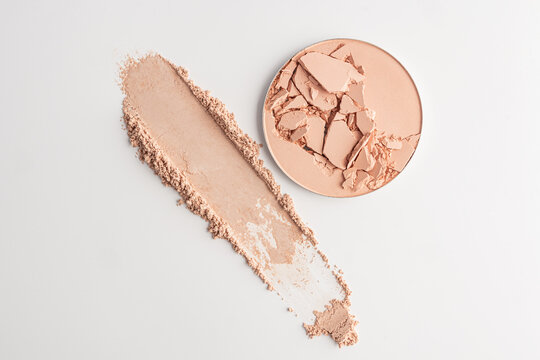 Cracked compact powder with cosmetic swatch on white background
