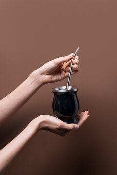 Female hand hold yerba mate cup with metal straw