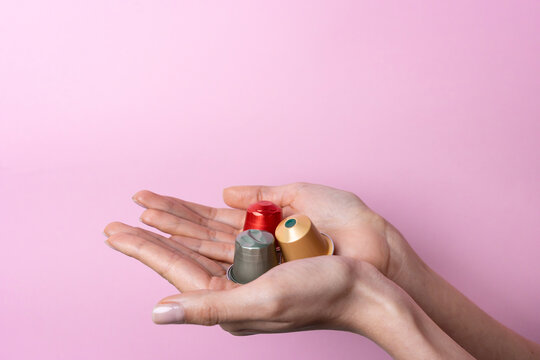 Female hands hold reusable bottle caps on pink background