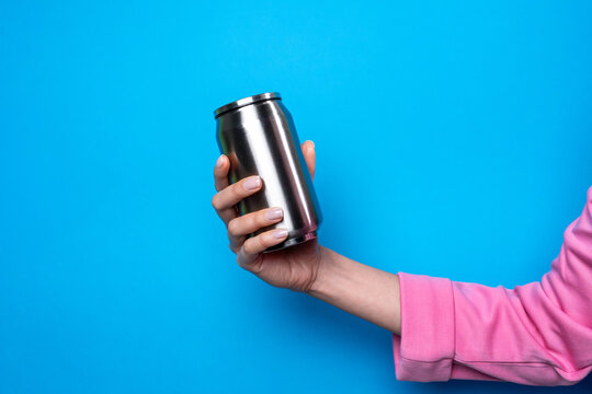 Woman hand hold reusable metal drink can on blue background