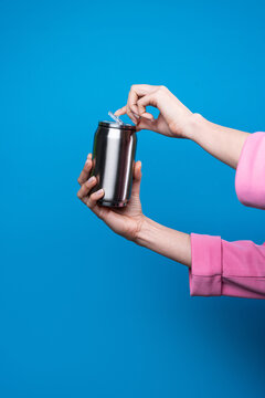 Female hand open drink can against blue background