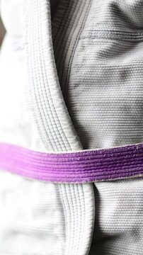 Vertical close up video of martial arts kimono go belt rank , close up selective focus, bokeh b roll martial arts, purple belt