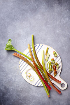 Fresh rhubarb stalk on striped board with peel curls