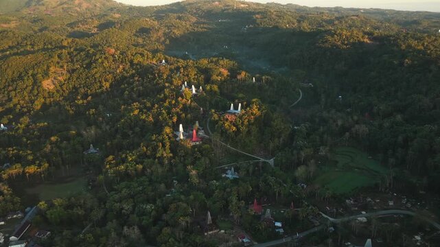 Aerial view of Wee Kacura traditional village with distinctive conical-roofed houses nestled in lush hills in Kecamatan Wewewa Timur, Nusa Tenggara Timur, Indonesia.