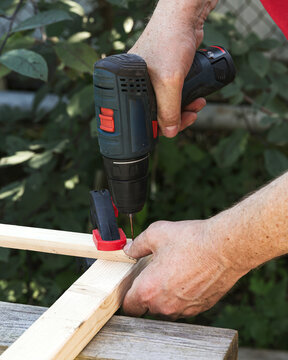 Woodworker use cordless drill for outdoor carpentry work