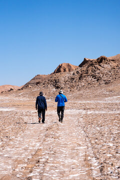 Hikers cross dry valley in Valle de Marte, Atacama, chile