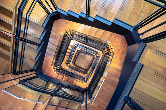 View of the spiral staircase with wooden steps and glass railings inside Tokyo Station in Chiyoda City, Tokyo, Japan.
