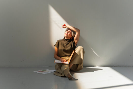 Mature businesswoman taking a break with folder in sunlight