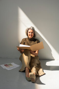 Mature businesswoman reviewing folder while seated in sunlight