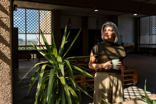 Mature woman with coffee in spacious industrial interior