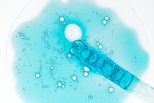 Blue serum bubbles and pipette on laboratory glass
