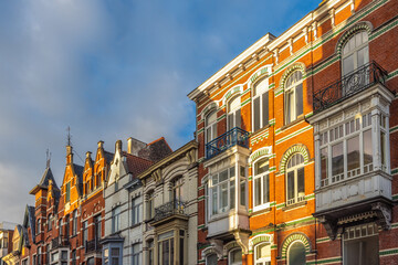 Fototapeta premium Historic European Architecture Lineup with Ornate Facades and Vibrant Brickwork Under a Bright Blue Sky. Ghent town in Belgium, Europe.