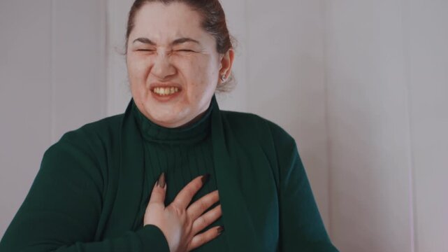 Teacher struggles breathing. Individual shows signs of labored respiration and tension. Instructor displays exhaustion and breathlessness while sitting against woodenpaneled wall with eyes shut