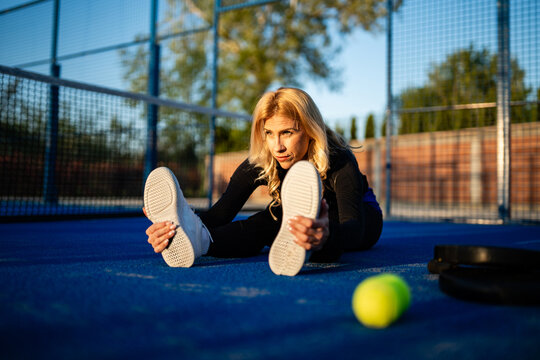 Woman stretching on blue padel tennis court