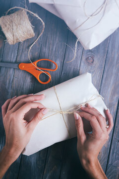 Christmas: Woman Ties Bow In String Around Gift