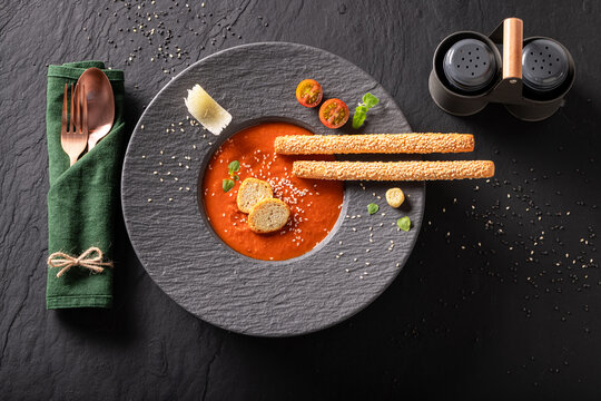 Professional and healthy tomato soup with high-end presentation on plate.