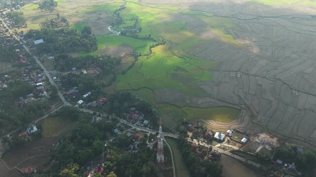 Aerial view of Kampung Prai Ijing surrounded by lush green rice fields and rural village houses under soft morning light in Kota Walkabubak, East Nusa Tenggara, Indonesia.