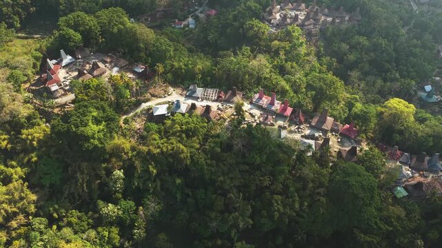 Aerial view of the traditional village of Kampung Prai Ijing with its iconic high-roofed houses nestled among lush green trees in Kota Walkabubak, East Nusa Tenggara, Indonesia.