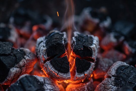 Charcoal embers glowing in a close up fire texture background