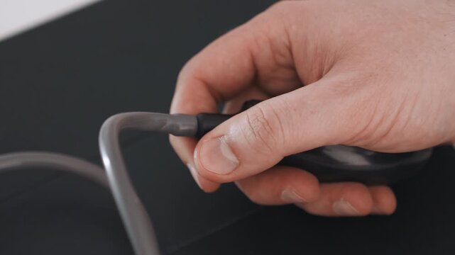 Closeup white technician hand adjusting small metal nozzle on black inflation bulb, calm remote monitoring setup for telehealth vitals, focused motion and precise connection details