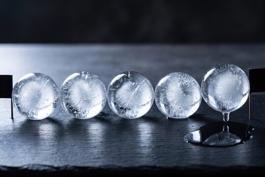 Melting ice spheres on dark surface with copy space background