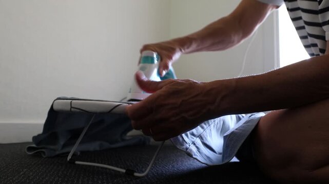 Gram, Denmark A woman irons a shirt on a miniature ironing board in a hotel room. 