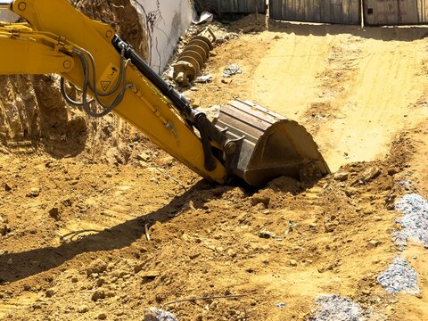 View of a yellow excavator bucket digging into the soil at a construction site in Sariyer, Istanbul, Turkiye.