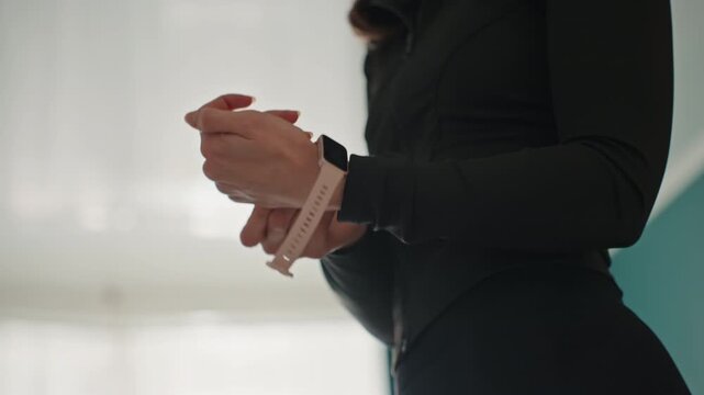 Hands fitting fitness tracker at home, closeup wrist band adjustment, silicone strap clasping, smartwatch device, black sleeve top, soft diffuse window light, precise sensor positioning, syncing