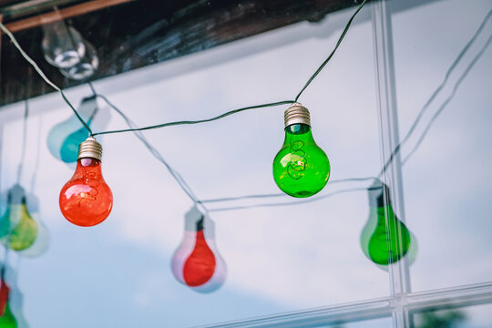 Colorful string lights with red and green glass bulbs hanging and creating a festive decorative display.