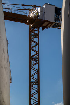 View of a yellow construction crane positioned between two buildings against a clear blue sky in Cascais, Lisbon, Portugal.