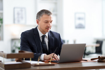 Fototapeta premium Lawyer working with laptop at wooden desk in office