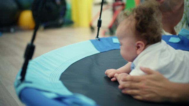 Toddler exercising on a therapy swing with a therapist helping develop motor skills and sensory integration